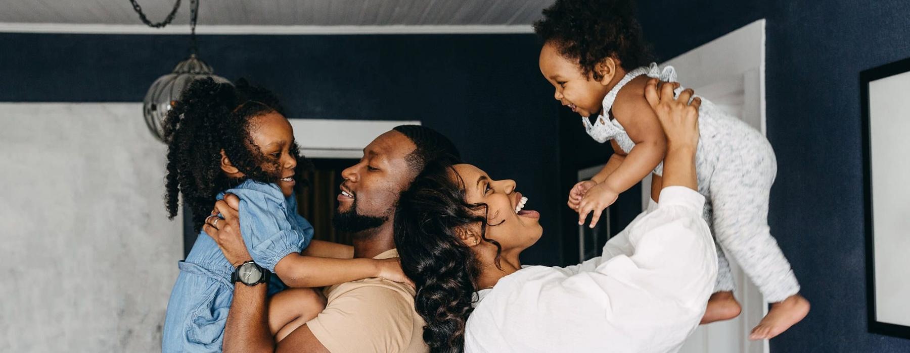 young parents hold up their children in room